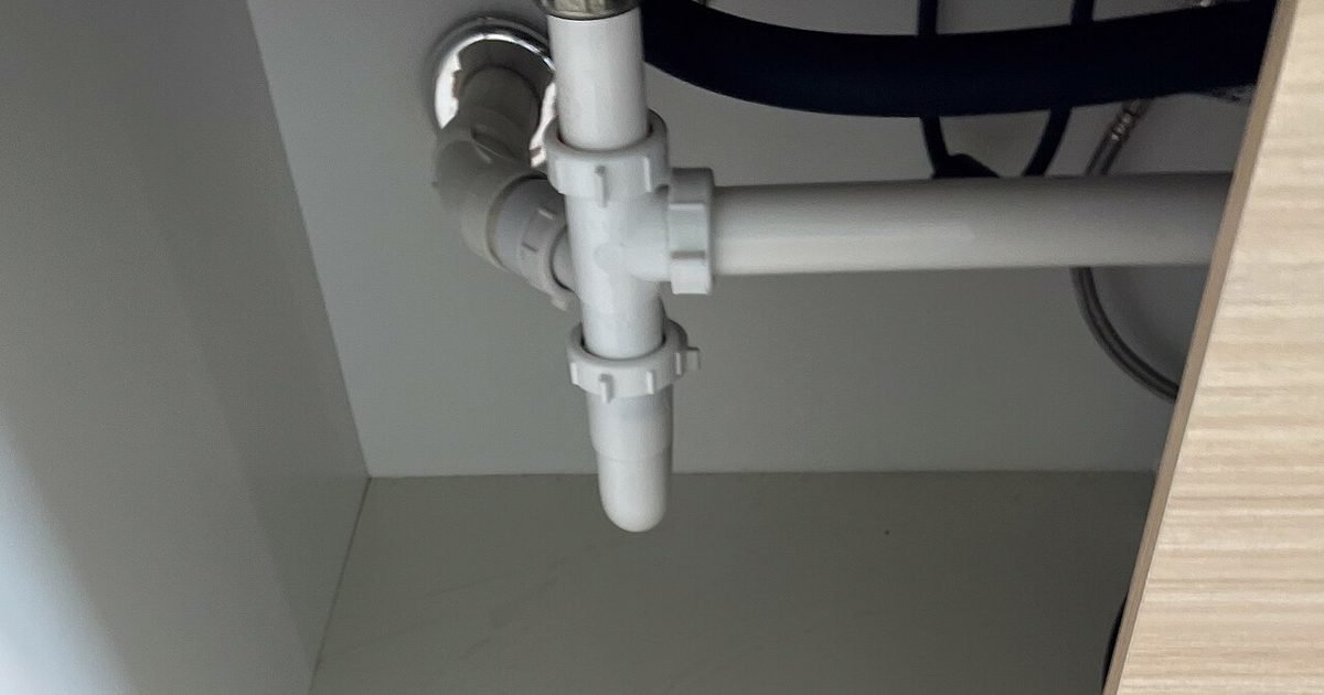 White PVC plumbing under a kitchen sink cabinet