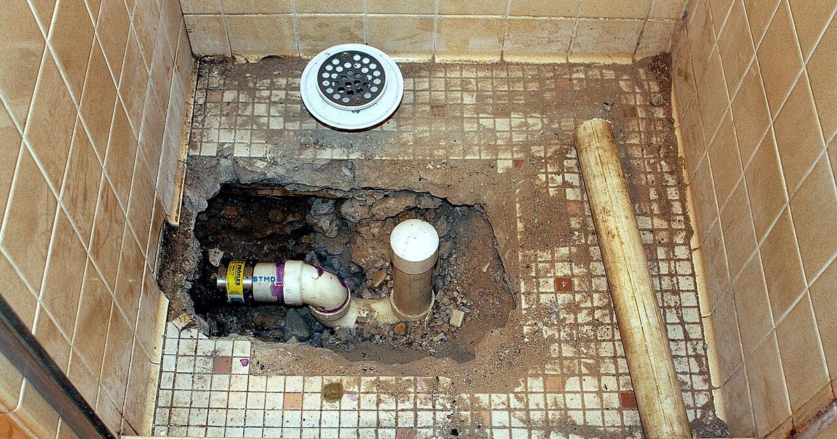 Tiled shower floor opened up to show the floor waste and the trap connection below the tiles