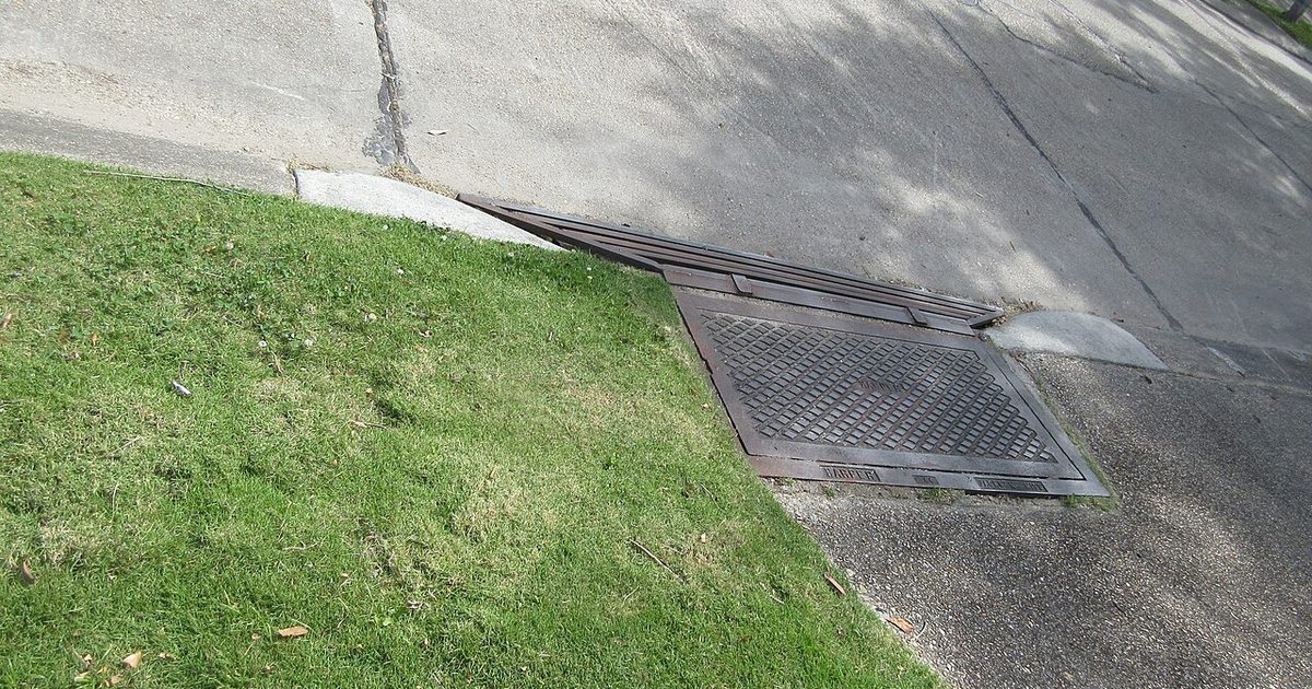 Driveway stormwater grate beside a grass verge