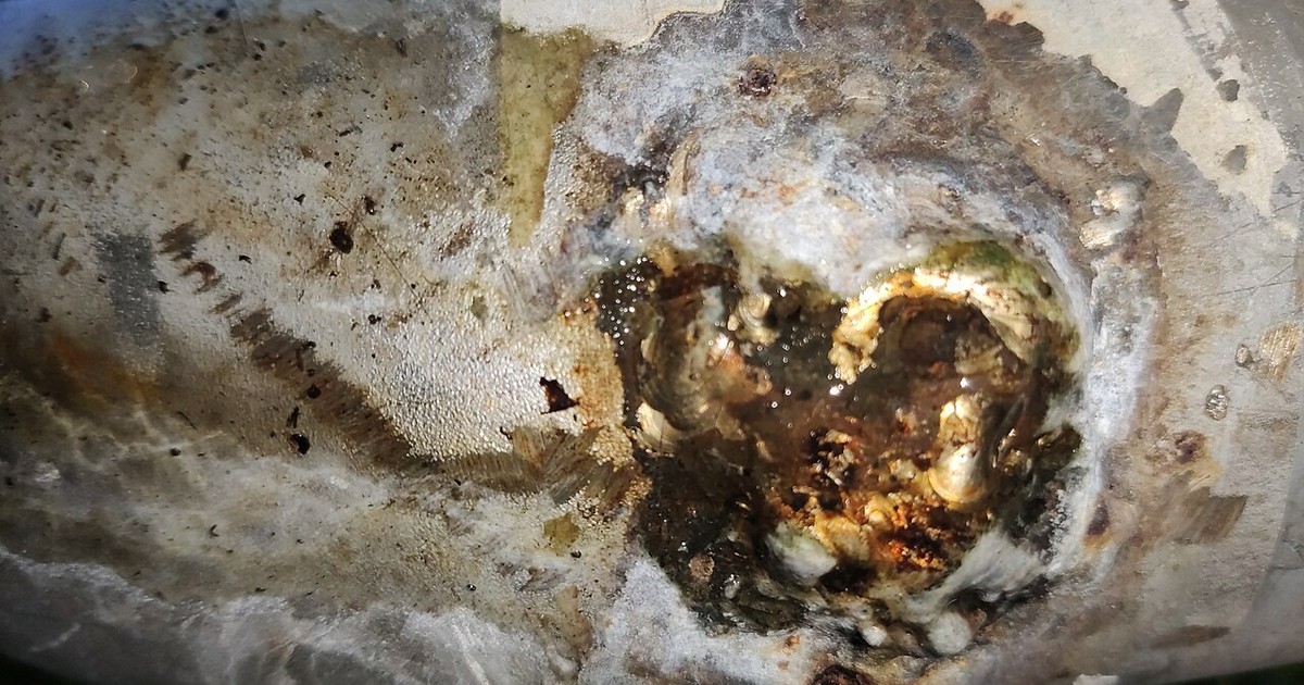 Close-up of a corroded pipe end with mineral build-up where the pipe has failed