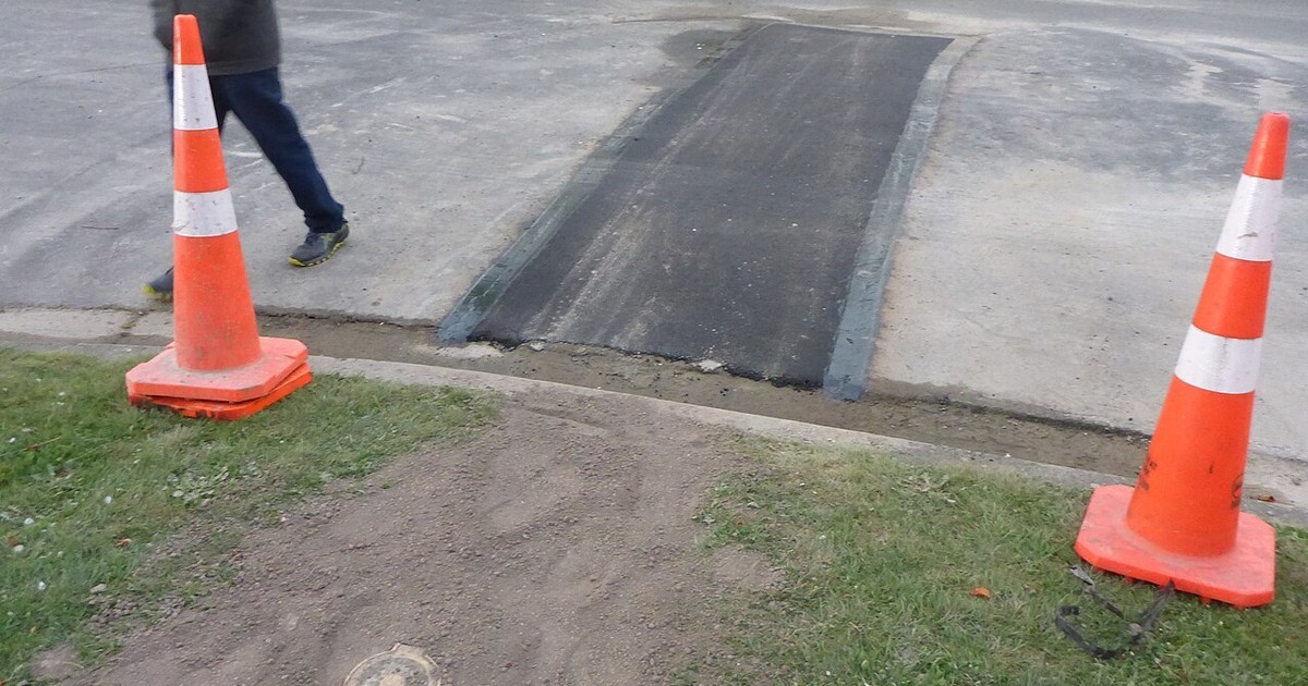 A water leak in a paved area cordoned off with safety cones
