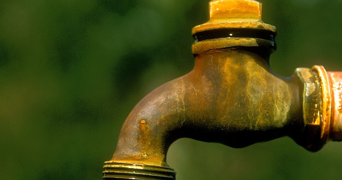An older brass tap fitted to an outdoor wall