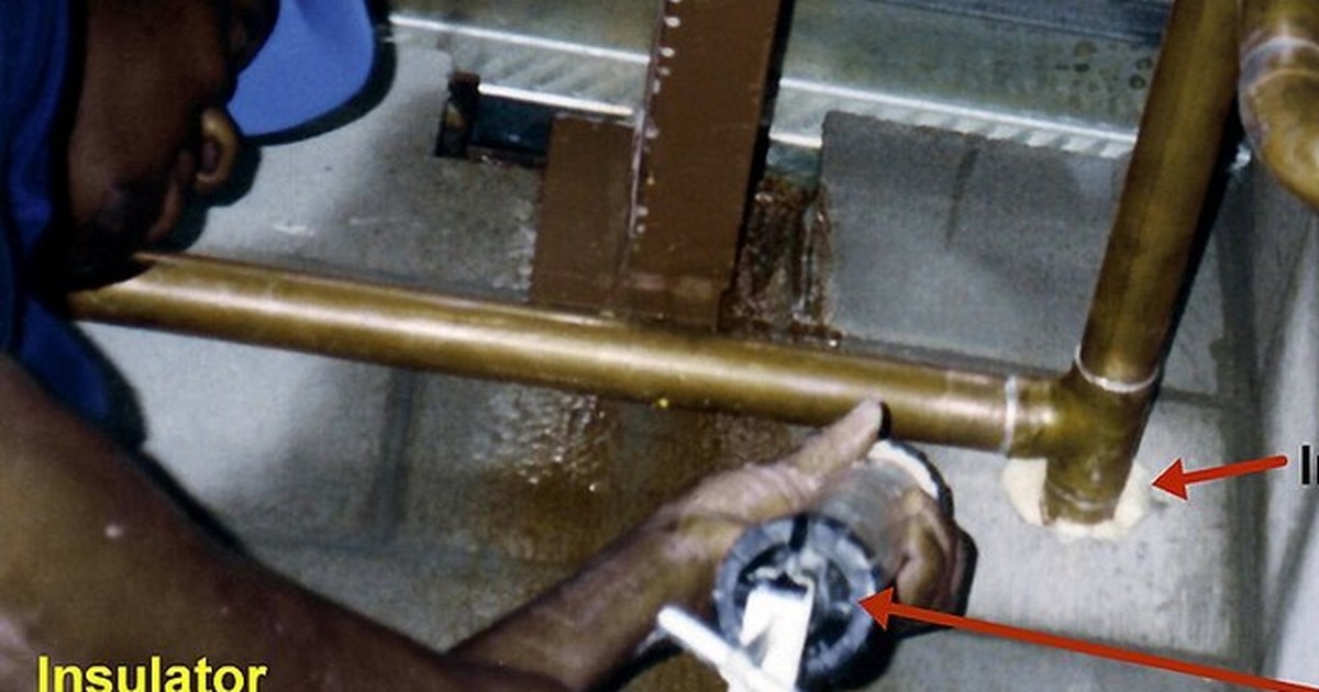 Hands fitting copper pipework with a caulking tool