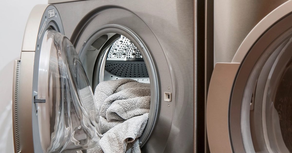 Front-loading washing machine in a laundry, showing the appliance space that affects hose and tap clearance