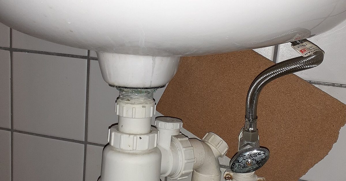 White trap and drain pipe under a sink, similar to the access needed below a laundry tub