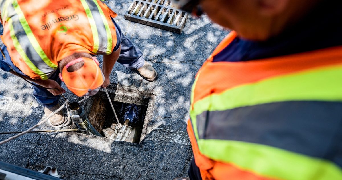 Drainage workers inspecting a pipe opening before repair
