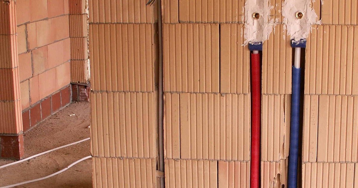 New red and blue plastic pipework fixed to a wall