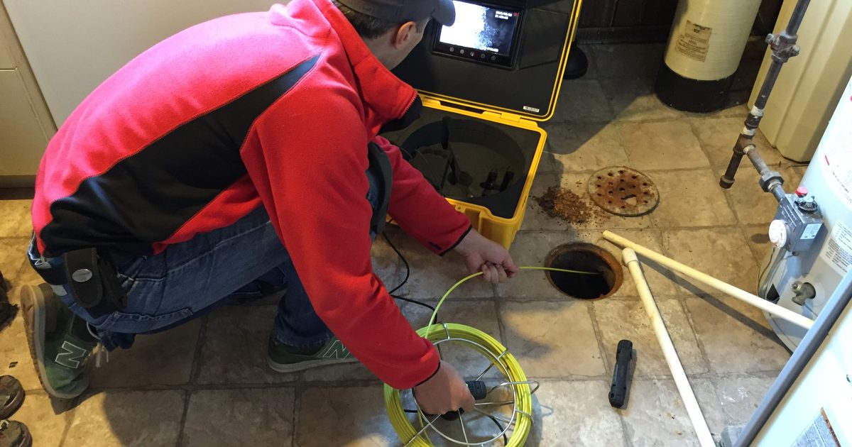 Plumber using a CCTV drain camera to inspect a pipe opening