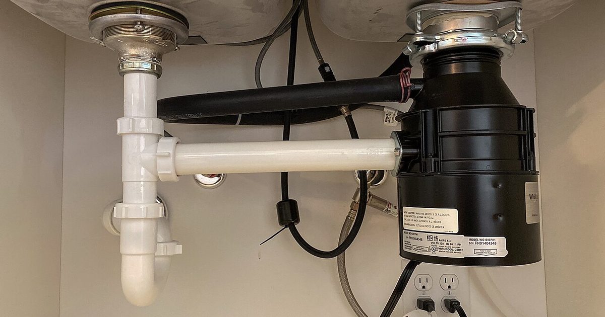 White under-sink waste pipe and garbage disposal plumbing
