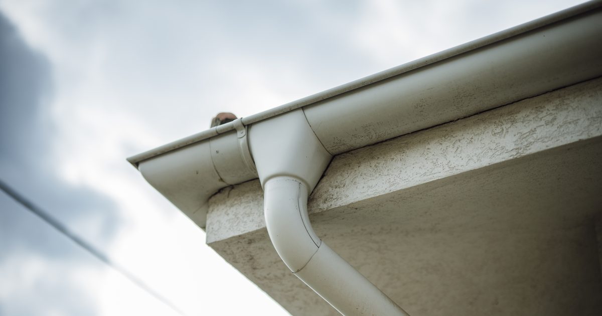 White roof gutter and downpipe on a house exterior