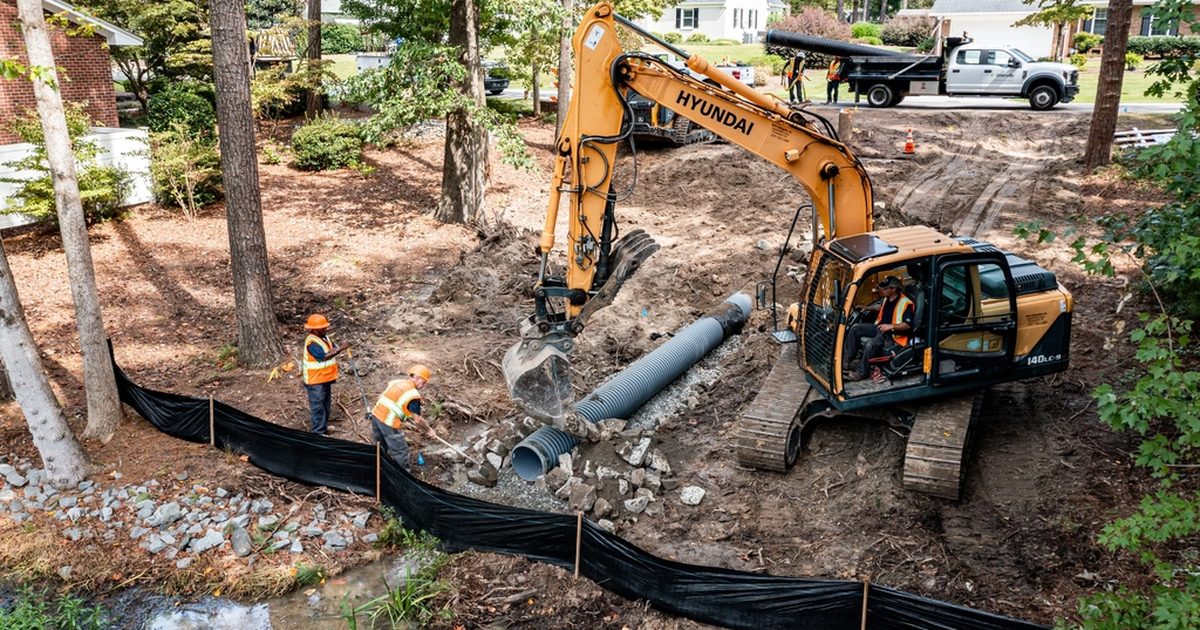 Excavation work around stormwater pipes beside trees