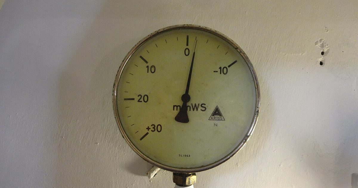 Round pressure gauge mounted on a wall for water pressure testing