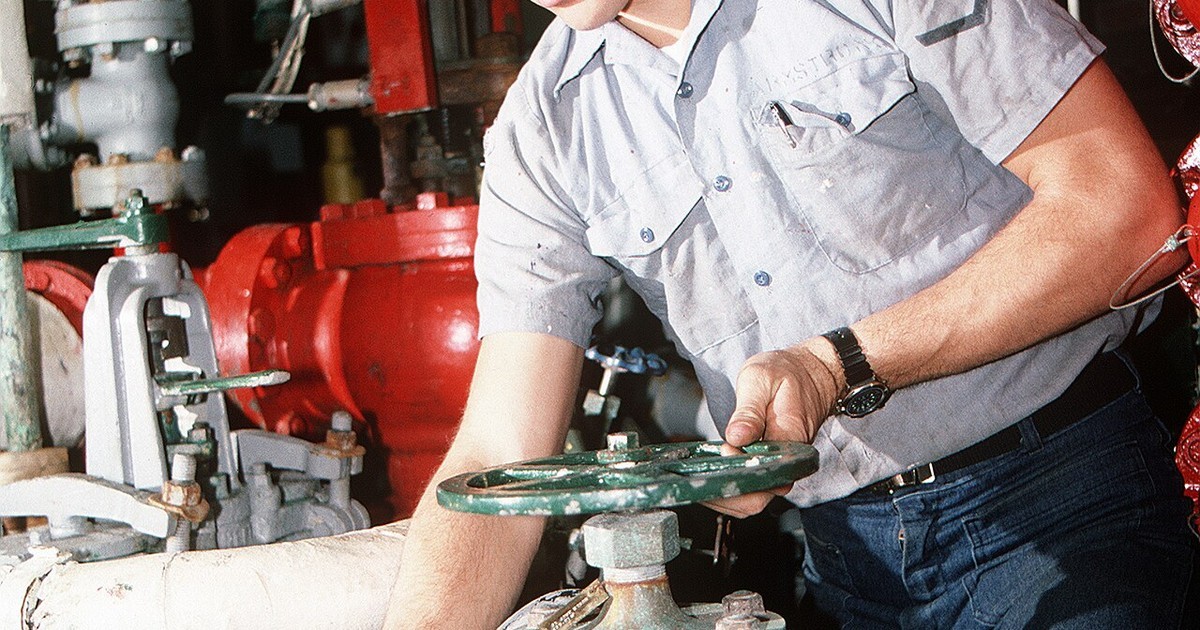 A technician turning a valve on heating equipment